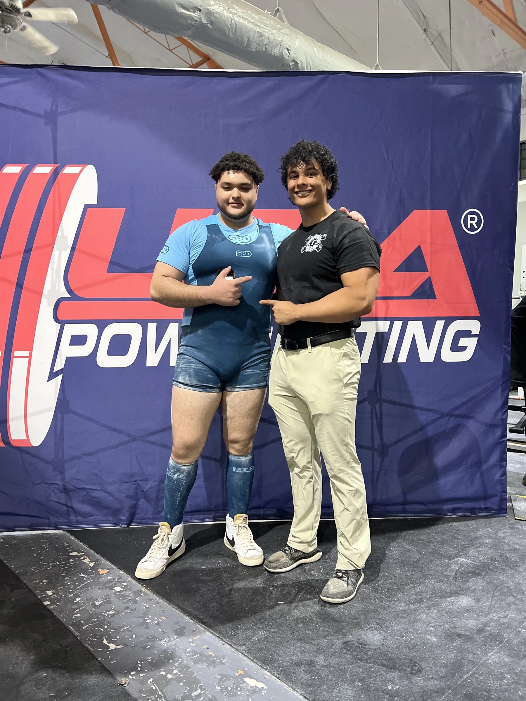 Two Forte Strength teammates in front of a USA Powerlifting backdrop after competing