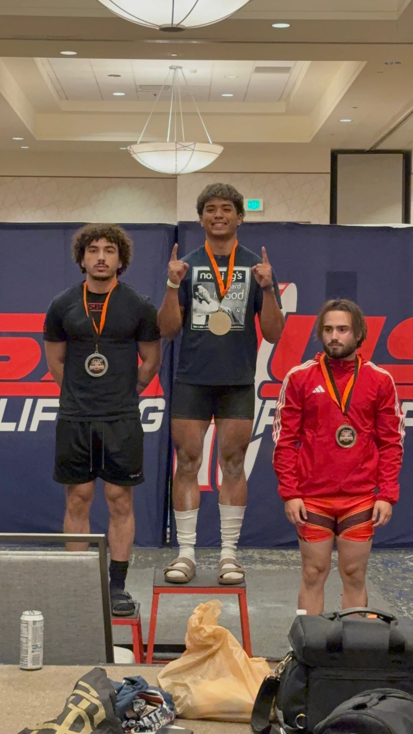 A Forte Strength athlete raising a trophy overhead on the podium